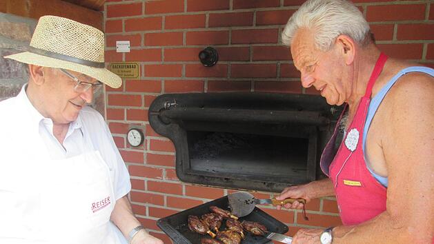 Die Vereinsmitglieder Hannes Deinlein (links) und Josef Keidel (rechts) garen "Mini-Haxen" im Insel-Backofen. Winfried Ehling