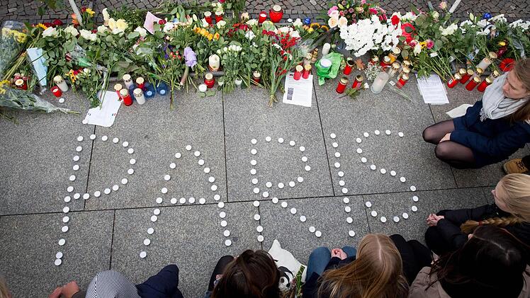 Menschen trauern am 14.11.2015 vor der französischen Botschaft am Brandenburger Tor in Berlin nach den Attentaten in Paris. Foto: Kay Nietfeld/dpa