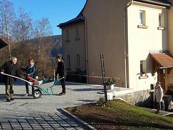 Eigenhändig fegen der evangelische Pfarrer Gerd Kirchner, dessen Ehefrau Martina und Sohn Jonathan (von links) den umgestalteten Hof mit den neuen Parkplätzen. Auch das Pfarrhaus am Auerhahnweg (rechts) wurde in die Sanierungsmaßahmen der vergangenen Monate mit einbezogen. Foto: Rolf Pralle