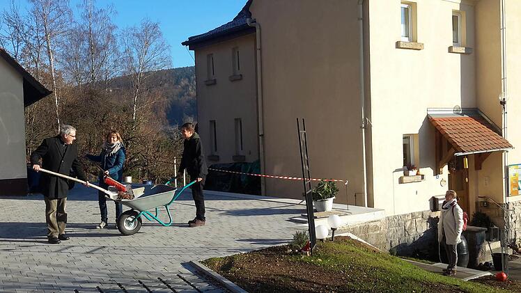 Eigenhändig fegen der evangelische Pfarrer Gerd Kirchner, dessen Ehefrau Martina und Sohn Jonathan (von links) den umgestalteten Hof mit den neuen Parkplätzen. Auch das Pfarrhaus am Auerhahnweg (rechts) wurde in die Sanierungsmaßahmen der vergangenen Monate mit einbezogen. Foto: Rolf Pralle