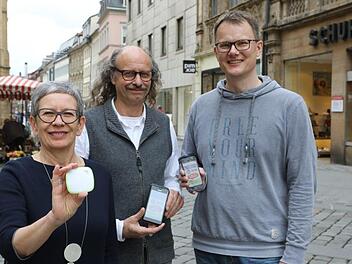 Birgid Bischoff und Manfred Hesse von "Kaufrausch" und Andreas Zeller von Schuh Zeller in Bamberg (rechts) zeigen ein Beacon und die Informationen auf dem Smartphone, die solch ein kleiner Sender übermitteln kann. Foto: Barbara Herbst