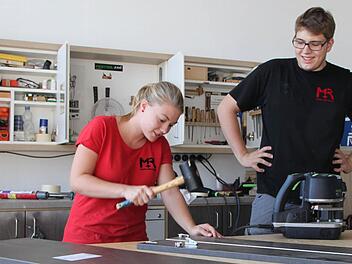 Echte Werkstatt-Atmosphäre: Anika Ferdin bringt Beschläge in fertig gebohrte Platten ein. Michael Remling schaut ihr über die Schulter. Anschließend wird das Möbelstück nur noch zusammengesetzt und verpackt. Foto: Ulrike Müller