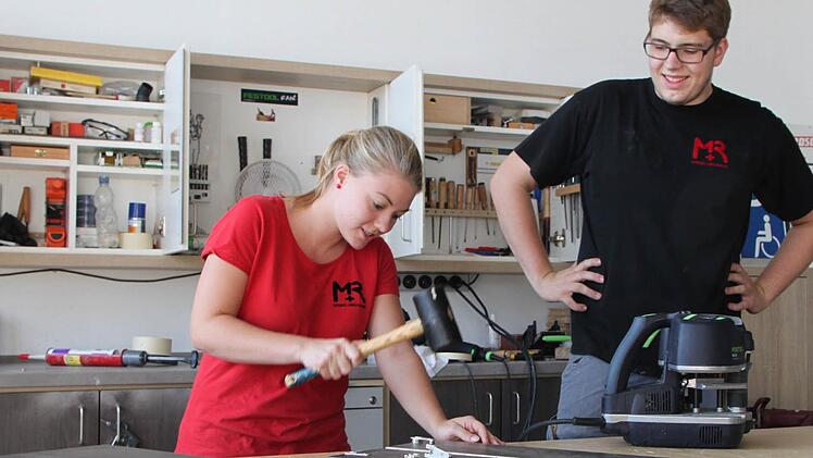 Echte Werkstatt-Atmosphäre: Anika Ferdin bringt Beschläge in fertig gebohrte Platten ein. Michael Remling schaut ihr über die Schulter. Anschließend wird das Möbelstück nur noch zusammengesetzt und verpackt. Foto: Ulrike Müller