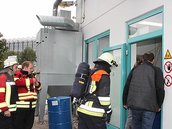 Gefahr gebannt: Feuerwehrleute und Mitarbeiter der Firma CoMI besichtigen die Produktionshalle, wo eine Abfüllmaschine für Industrietinte gebrannt hatte. Foto: Stephan Tiroch