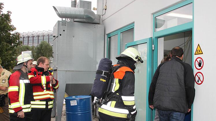 Gefahr gebannt: Feuerwehrleute und Mitarbeiter der Firma CoMI besichtigen die Produktionshalle, wo eine Abfüllmaschine für Industrietinte gebrannt hatte. Foto: Stephan Tiroch