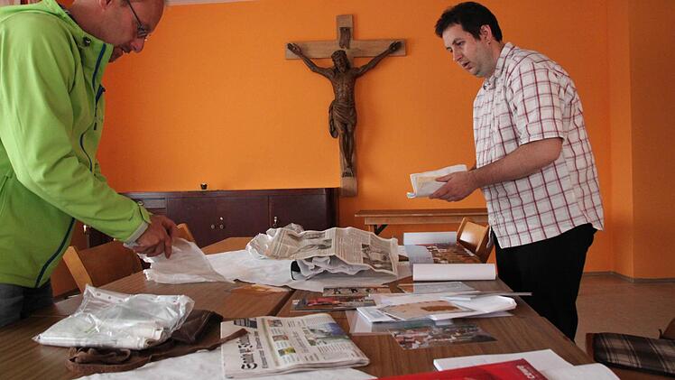Jürgen Meder und Bjrön Hein sortieren die Unterlagen, die in die Kirchturmkugel gegeben werden sollen. Foto: Heike Beudert