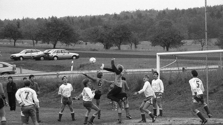 Auto-Modelle und Haar-Mode weisen deutlich auf die 80er Jahre hin. Anfang Oktober 1989 duellieren sich der TSV Wollbach und der FSV Schönderling. Foto: E.E. Kunstmann