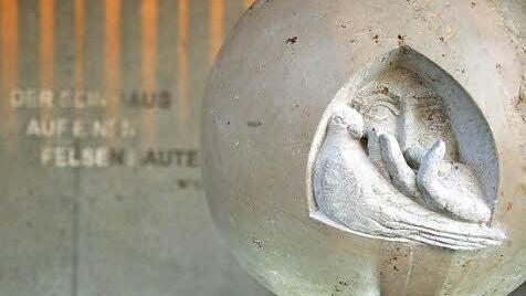 Das von Ralf Hartan geschaffene Kunstwerk: Eine aus Jurakalk gearbeitete Kugel mit einem auf Fuchsstadt blickenden Gesicht, einer Hand und einer Taube. Der Mittelpunkt der Kapelle symbolisiert die Dreifaltigkeit: Gott Vater, seinen Mensch geworden Sohn Jesus und den Heiligen Geist.