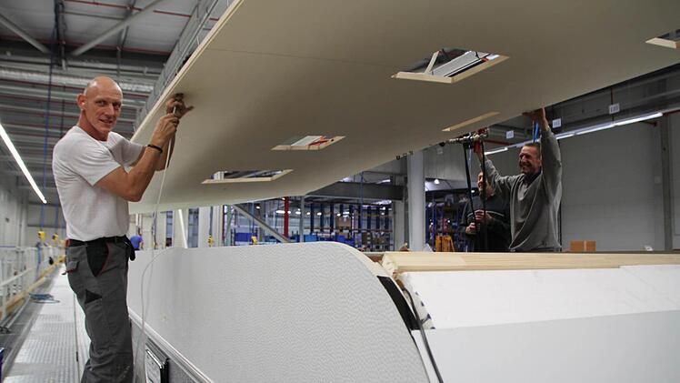 Horst Muth (links) aus Oehrberg montiert mit seinen Kollegen das Dach auf den Wohnwagen.