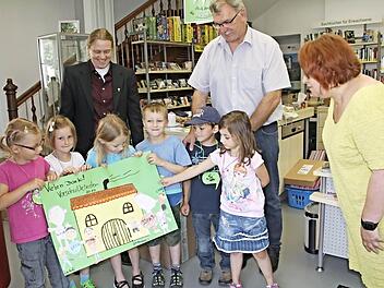 Freudestrahlend zeigten die Kinder ihr Plakat, welches sie unter den Augen von Pfarrerin Sonja von Aschen und Bürgermeister Helmut Dietz (hinten von links) an die Leiterin des Komm, Ute Morgenroth (rechts) übergaben.  Foto: Helmut Will
