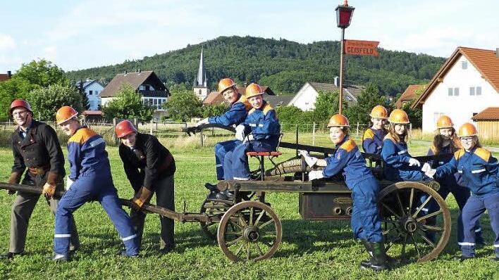 Alt und Jung sind startklar für das 130-jährige Feuerwehrjubiläum. Die Geisfelder Jugendfeuerwehr mit den Kommandanten Dietmar Einwich (links) und dem Vorsitzenden des Feuerwehrvereins Thomas Uzelino (Dritter von links) an der alten Feuerwehrspritze aus dem Gründungsjahr 1884. Foto: Andrea Spörlein