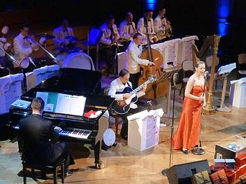 Im Vordergrund aufgetürmte Geschenkschachteln und am Ende eine Weihnachtspalme: Das Swing Dance Orchestra, hier mit der Sängerin Bettina Labeau, brachte die Spielart der US-amerikanischen Weihnachtsstimmung in den Großen Saal. Foto: Thomas Ahnert