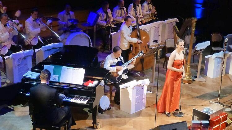 Im Vordergrund aufgetürmte Geschenkschachteln und am Ende eine Weihnachtspalme: Das Swing Dance Orchestra, hier mit der Sängerin Bettina Labeau, brachte die Spielart der US-amerikanischen Weihnachtsstimmung in den Großen Saal. Foto: Thomas Ahnert