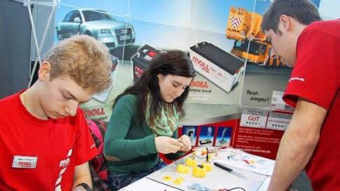 Die beiden Auszubildenden Andreas Wegner (li.) und Lukas Baldauf (re.) erklären Svenja Moch (Mitte) ein physikalisches Experiment.