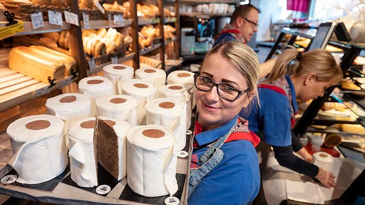 Eine Verkäuferin der Bäckerei Schürener Backparadies zeigt im Verkaufsraum ein Blech mit runden Marmorkuchen, die mit Fondant umwickelt wie Toilettenpapier-Rollen aussehen. Der Klopapier-Kuchen von Bäcker Kortüm ist in der Corona-Krise zu einem ·Bestseller· geworden. Foto: Bernd Thissen/dpa