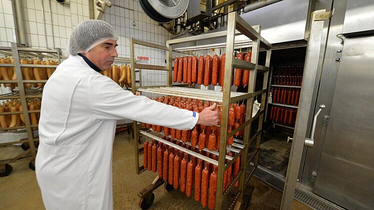 Nachtschichtleiter Hubert Stussak holt Mettwurst aus der Räucherkammer. Foto: Ronald Rinklef
