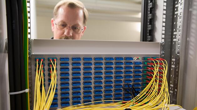 Die Gemeinde Altenkunstadt baut ihr eigenes Glasfasernetz und &uuml;bergibt den Betrieb an den wirtschaftlichsten Betreiber. Das Bild zeigt einen Techniker bei seiner Arbeit an einem Glasfaserkabelschrank.  Foto: Telekom