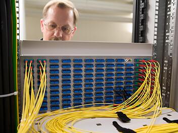 Die Gemeinde Altenkunstadt baut ihr eigenes Glasfasernetz und übergibt den Betrieb an den wirtschaftlichsten Betreiber. Das Bild zeigt einen Techniker bei seiner Arbeit an einem Glasfaserkabelschrank.  Foto: Telekom