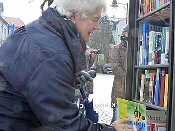 Gisela Wolf steckt ein weiteres Buch in den gut gefüllten offenen Bücherschrank. Foto: Rainer Lutz