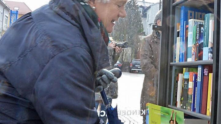 Gisela Wolf steckt ein weiteres Buch in den gut gefüllten offenen Bücherschrank. Foto: Rainer Lutz