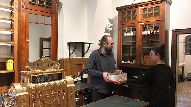 Alexander Mohr und Nicole Sippel beim Einr&auml;umen der antiken Apothekerschr&auml;nke. Die mechanische Registrierkasse auf der Theke    ist &uuml;ber 100 Jahre alt, restauriert und  voll funktionsf&auml;hig.Ulrike Nauer