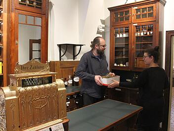 Alexander Mohr und Nicole Sippel beim Einräumen der antiken Apothekerschränke. Die mechanische Registrierkasse auf der Theke    ist über 100 Jahre alt, restauriert und  voll funktionsfähig.Ulrike Nauer