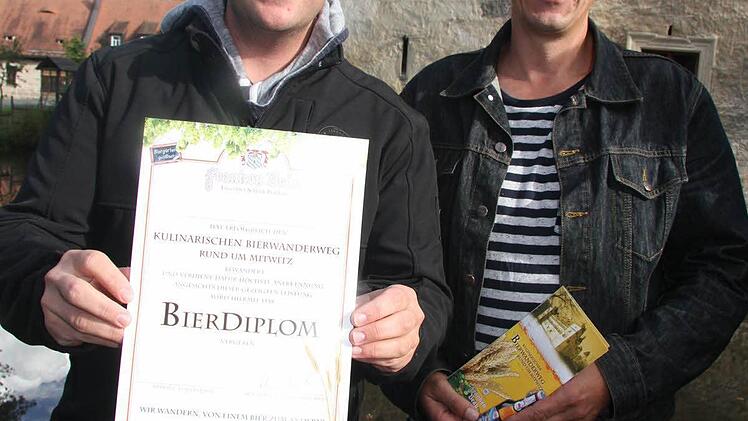 Wanderlustige, die mindestens vier Stempel von unterschiedlichen Stationen auf dem Mitwitzer Bierweg vorweisen können, erhalten ein Bier-Diplom. Allerdings geht es nicht nur ums Bier, sondern auch um kulinarische Erlebnisse, erklären Oliver Schwämmlein (links) und Ralf Heidelberger.