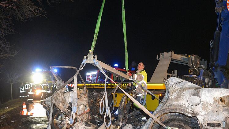 Sachsen-Anhalt, K&ouml;then: Feuerwehrleute und Rettungskr&auml;fte stehen auf einer Landstra&szlig;e hinter einem ausgebrannten Auto. Bei dem Autounfall sind drei Menschen, darunter ein Kind, verbrannt. Ein S&auml;ugling wurde aus dem Wrack gerettet. Foto: Heiko Rebsch/dpa-Zentralbild/dpa