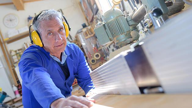 Schreiner schleift Holzmaterialien, alter Mann arbeitet