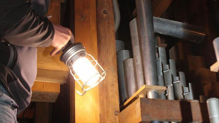 Ohne die Lampe sieht Heinemann nur wenig hinter der Orgel.