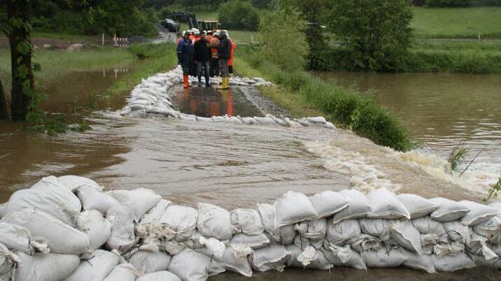 Dass die Aurach über die Ufer tritt und in die Tretzendorfer Weiher fließt, war nicht zu verhindern. Immerhin aber gelingt es den Feuerwehrleuten und anderen Helfern, die Strömungen mit Hilfe von Sandsäcken zu kontrollieren. Fotos: Sabine Weinbeer