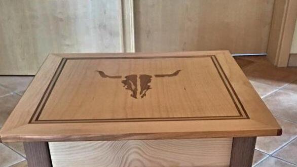 Hocker mit Beinen aus Nussbaum und Schubladenformat aus Kiefer mit dem Logo des Wacken Open Air Festivals, hergestellt von Svenja Hastedt am Ende ihre BGJ . Foto: Svenja Hastedt.