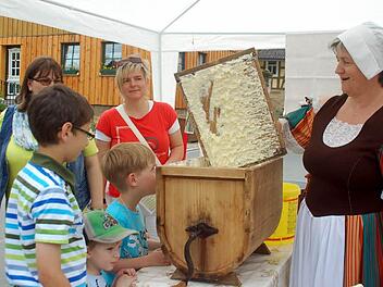 Und so hat die Oma einst die Butter zubereitet: Karin Kochmann zeigt den staunenden Kindern, wie ein Butterfass funktioniert. Foto: Gabi Arnold