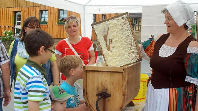 Und so hat die Oma einst die Butter zubereitet: Karin Kochmann zeigt den staunenden Kindern, wie ein Butterfass funktioniert. Foto: Gabi Arnold