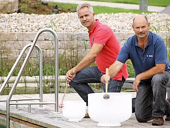 Die Saunameister Peter Diller (links) und Roland Müller bereiten gemeinsam mit vielen anderen das "Sauna-Opening" vor. Die beiden wirken bei den "Aqua-Soleros" mit, die ein Musical für diesen Abend zusammengestellt haben. Hier proben sie gerade mit den Klangschalen aus Kristall, die auf der "Bühne" am neuen Badesee erklingen werden. Foto: Matthias Einwag