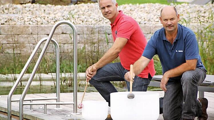 Die Saunameister Peter Diller (links) und Roland Müller bereiten gemeinsam mit vielen anderen das "Sauna-Opening" vor. Die beiden wirken bei den "Aqua-Soleros" mit, die ein Musical für diesen Abend zusammengestellt haben. Hier proben sie gerade mit den Klangschalen aus Kristall, die auf der "Bühne" am neuen Badesee erklingen werden. Foto: Matthias Einwag