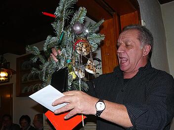 Auktionator Kurt Franz preist die am Ast hängenden Utensilien an und bittet um Gebote. Foto: Klaus-Peter Wulf