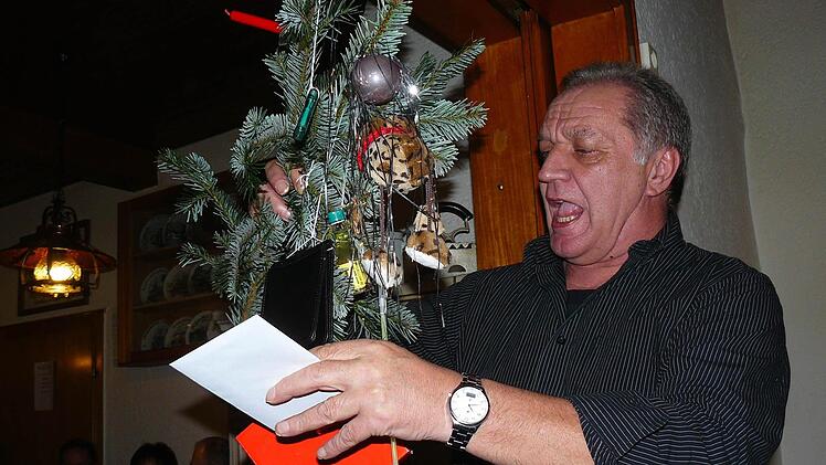 Auktionator Kurt Franz preist die am Ast hängenden Utensilien an und bittet um Gebote. Foto: Klaus-Peter Wulf