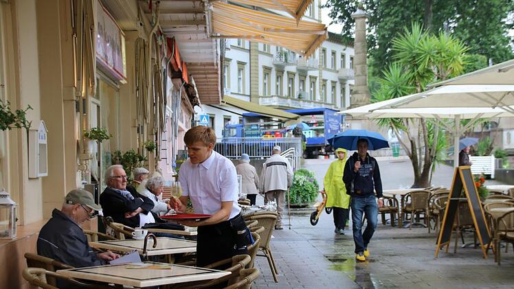 Die Gastronomen der Stadt haben trotz Regenwetter gut zu tun - Dank zahlreicher überdachter und beschirmter Plätze. Hier bedient Kellner Robert einen Gast vorm Café am Rosengarten. Foto: K. Kupka-Hahn