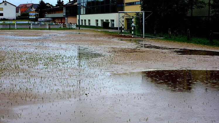 Auch gestern war der Nebenplatz im Sander Seestadion (im Hintergrund die Turnhalle) von Wasserpfützen übersät und unbespielbar. An seiner Stelle soll ein Kunstrasenplatz entstehen. Die Sander bemühen sich um Fördergeld für ein "Multikulturelles Gemeindezentrum". Foto: ab