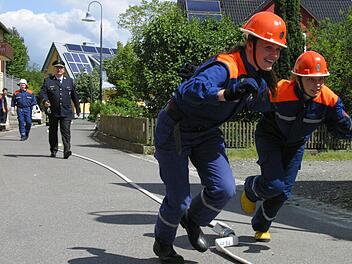 Beim Zusammenkuppeln einer 60 Meter langen C-Leitung kamen die Teilnehmer ganz schön ins Schwitzen und Schnaufen. Nicht selten waren die Mädchen, wie hier Katharina Bätz (rechts) und Anna-Lena Gehrlicher vom Team Großgarnstadt/Pülsdorf, schneller, wie Kreisbrandmeister Bernd Schultheiß (Bildmitte) bestätigte. Foto: Bettina Knauth