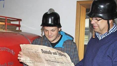 Mit "Pickelhaube" und historischen Schlagzeilen: Feuerwehrkommandant Bastian Hauck und Stadtteilvertreter Thomas Limpert. Foto: Ralf Kestel