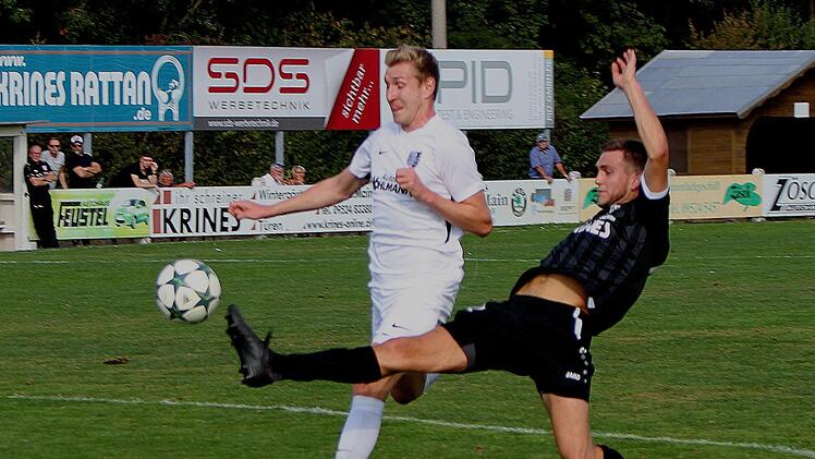 Den angesichts der Umst&auml;nde unerwarteten Torreigen er&ouml;ffnete der Sander Christopher Gonnert (rechts), als er hier noch mit langem Bein durchst&ouml;&szlig;t und den Ball am Karlburger Marco Schiebel vorbei ins untere linke Tordreieck spitzelt. Foto: G&uuml;nther Geiling