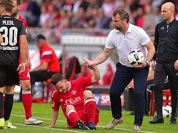 Immer wieder aufstehen: W&uuml;rzburgs Trainer Bernd Hollerbach (2.v.r.) holt nach einem Foulspiel den Ball und zieht seinen Spieler Peter Kurzweg (M) nach oben, um einen Zeitverlust zu vermeiden. Die W&uuml;rzburger Kickers sind nach der Pleite gegen Sandhausen auf den 17. Tabellenplatz abgerutscht. Foto: dpa