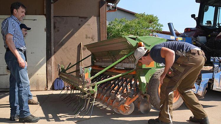 Prüfling Dominik Lieb dreht ab, sagen die Fachleute. Damit ist ein Testlauf der Sämaschine gemeint, um die richtige Menge des Saatgutes zu bestimmen. Seine Prüfer Herbert Lang, Leiter des AELF Schweinfurt (rechts) und Stefan Büttner, Landwirt aus Oberwaldbehrungen, schauen genau zu. Foto: Kathrin Kupka-Hahn