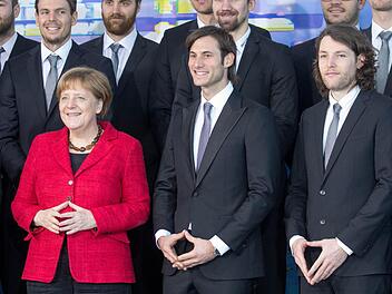 Original und Fälschung: Die deutschen Handballer Uwe Gensheimer (vorn/M) und Johannes Sellin (vorn/r) in Merkel-Pose. Links das Orignal von Kanzlerin Merkel. Foto: Michael Kappeler/dpa