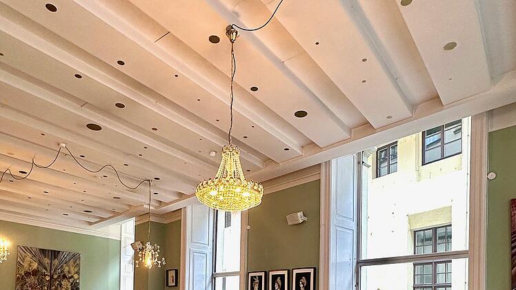 Helles Caf&eacute; mit Holzfu&szlig;boden und eleganter Einrichtung. Kronleuchter, gro&szlig;e Fenster, Kunstwerke an den W&auml;nden und verschiedene Sitzbereiche verleihen dem Raum eine gem&uuml;tliche Atmosph&auml;re.