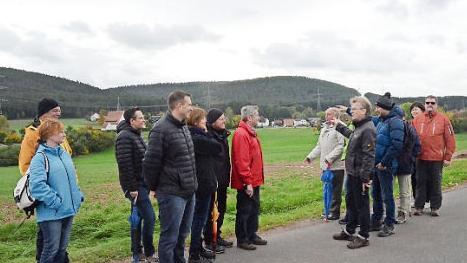 Bürgermeister Rainer Detsch zeigt auf die bestehende Stromtrasse (im Hintergrund) direkt in Haig. Mit im Bild der Freie-Wähler-Kreisvorsitzende Tino Vetter (links) und Stockheims Vorsitzender Stefan Häfner ( vierter von links). Foto: Karl-Heinz Hofmann