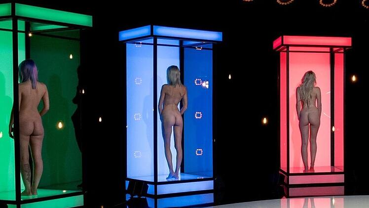 Moderatorin Milka Loff Fernandes posiert vor den Boxen, in denen sich die Kandidaten bei "Naked Attraction" zur Schau stellen. (Foto: © RTL II / Claudius Pflug)
