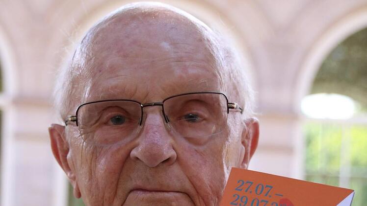 Johannes Mohr ist gemeinsam mit seiner Frau in Bad Kissingen. "Wir sind hier zum Urlaub machen." Nachdem sie eher zufällig erfahren haben, dass das größte Fest des Jahres vor der Tür steht, wurden die beiden gleich aktiv: "Die Pins für das Rakoczy-Fest haben wir uns  schon gekauft." Zusammen mit seiner Frau Ruth teilt der 89-Jährige eine klare Meinung zum Design der Produkte rund ums Rakoczy-Fest: "Ich finde, dass das neue schöner ist." Als geschickt umgesetzt empfindet er auch die Flyer: "Di...